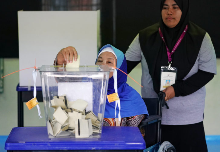 A woman in a wheelchair casts her ballot at a polling station during Malaysia's general election in Pekan