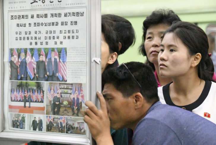 North Koreans watch the displayed local newspapers reporting the summit between the U.S. and North Korea at a subway station in Pyongyang