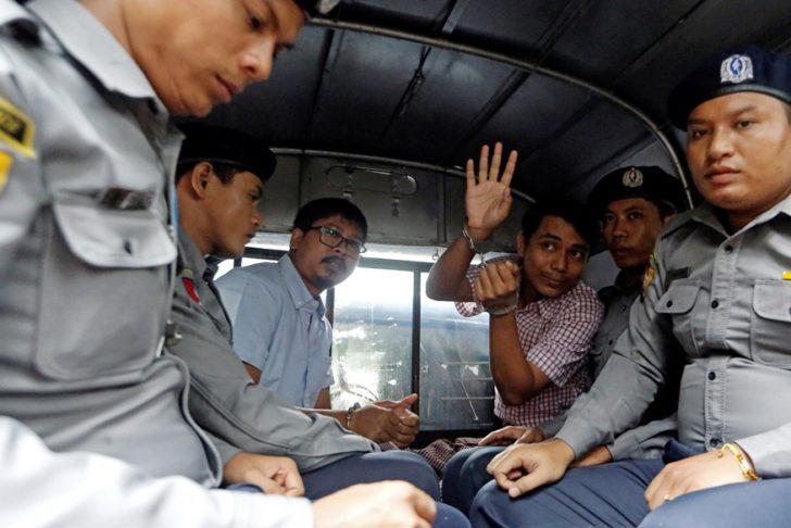 Detained Reuters journalist Wa Lone and Kyaw Soe Oo sit beside police officers as they leave Insein court in Yangon