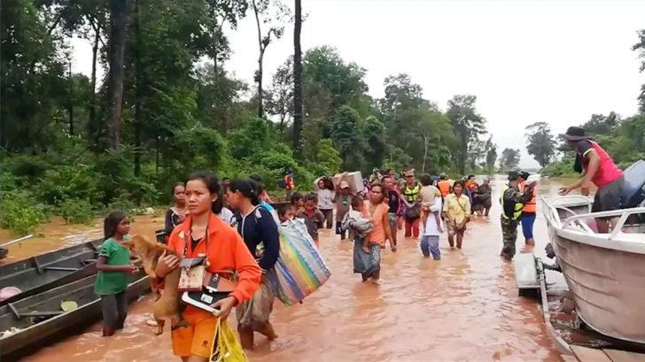 People walk through flooded area after being brought to safety by boat in Sanam Xay district, Attapeu Province, Laos after a hydropower dam under construction in Southern Laos collapsed, in this still picture taken from social media video