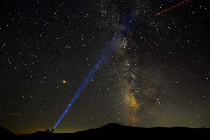 A man points his light at the Milky Way during the peak of the Perseid meteor shower in Macedonia