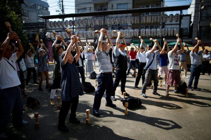 Elderly and middle-aged people exercise with wooden dumbbells during a health promotion event to mark Japan's