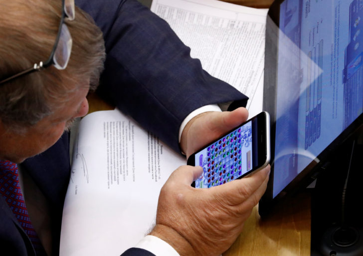 A Russian lawmaker plays a game on his mobile phone during a vote on the pension reform bill at the State Duma in Moscow