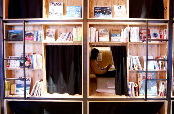 A woman reads a book at a bed room at the Shinjuku branch of Book and Bed, an accommodation combined with book cafe where guests can sleep in hidden bunks built into a large bookshelf, during a photo opportunity in Tokyo