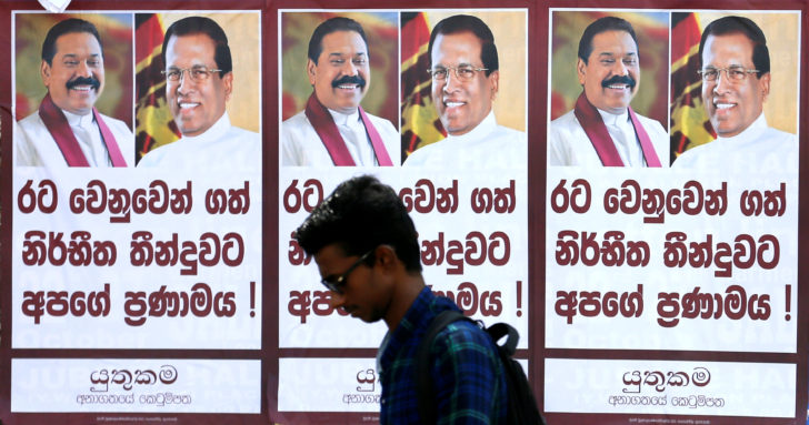 A man walks past a poster of Sri Lanka's newly appointed Prime Minister Mahinda Rajapaksa and President Maithripala Sirisena on a main road in Colombo