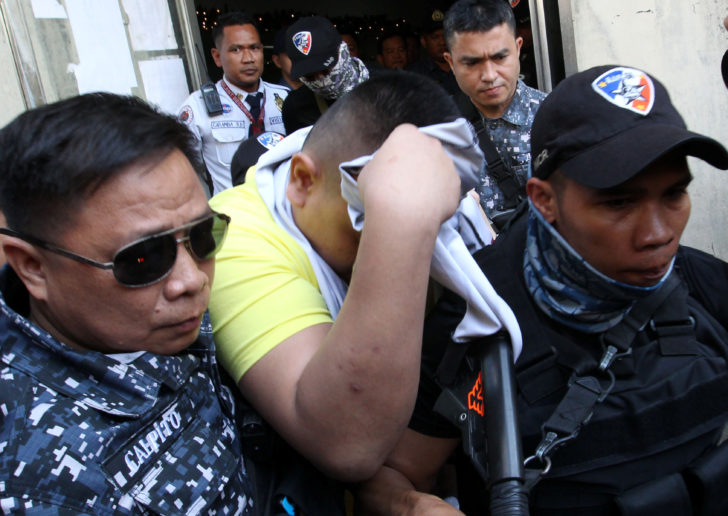A police officer covers his face as he is escorted after his sentencing for the murder of a 17-year-old high school student, in Manila