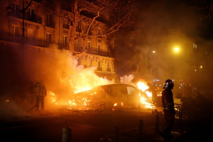 Firemen extinguish burning cars set afire by protesters wearing yellow vests, a symbol of a French drivers' protest against higher diesel fuel taxes, during clashes near the Place de l'Etoile in Paris