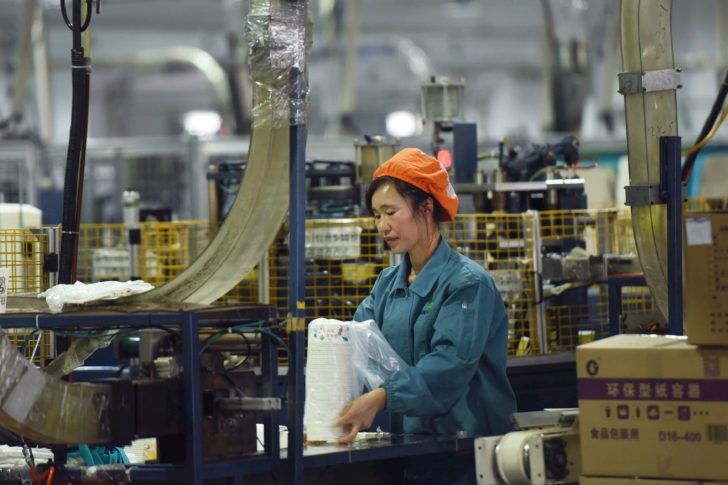 Woman works on a production line manufacturing paper tableware at a factory in Hangzhou, Zhejiang