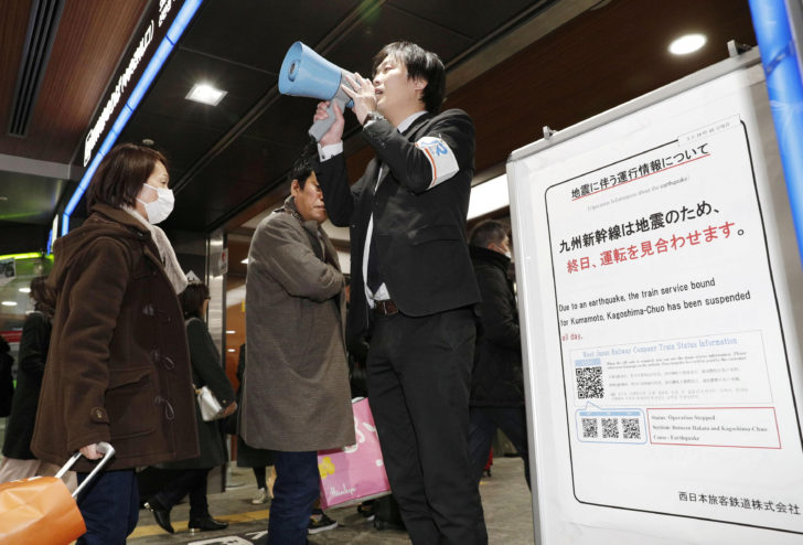 An employee of West Japan Railway Company announces information to passengers after an earthquake at Hakata station in Fukuoka