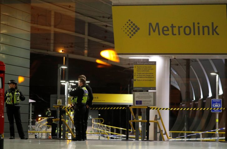 Police officers stand at the end of a tram platform following a stabbing at Victoria Station in Manchester