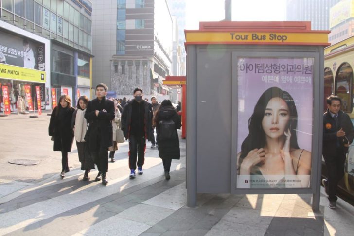 A woman passes by a plastic surgery advertisement at the Gangnam district in Seoul, South Korea January 11, 2019. THOMSON REUTERS FOUNDATION/Seulki Lee