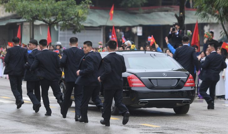 North Korean bodyguards run along a limousine transporting North Korea's leader Kim Jong Un upon his arrival at the border town with China in Dong Dang