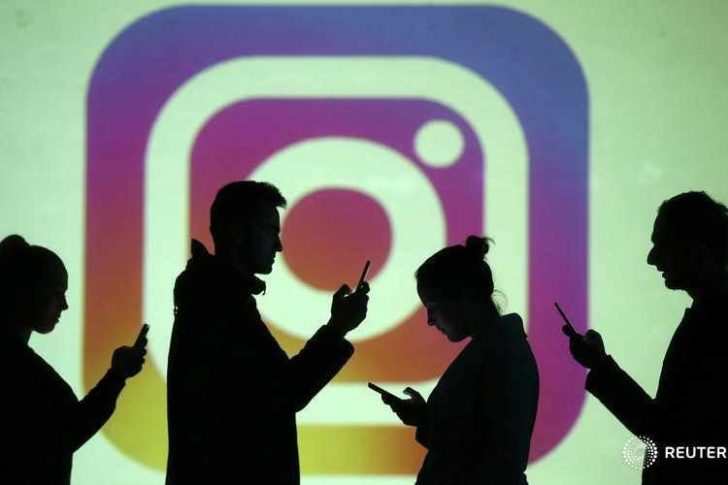 Silhouettes of mobile users are seen next to a screen projection of Instagram logo in this picture illustration