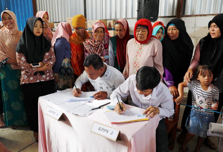 People wait for registration at a polling booth during elections in Bogor