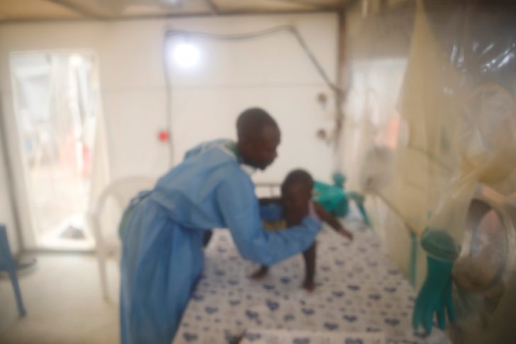 An infant Ebola patient is tended to by an Ebola survivor inside the Biosecure Emergency Care Unit at the ALIMA Ebola treatment centre in Beni