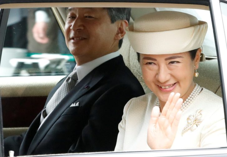 Japan's Empress Masako waves from a vehicle as she arrives with Emperor Naruhito at the Imperial Palace in Tokyo
