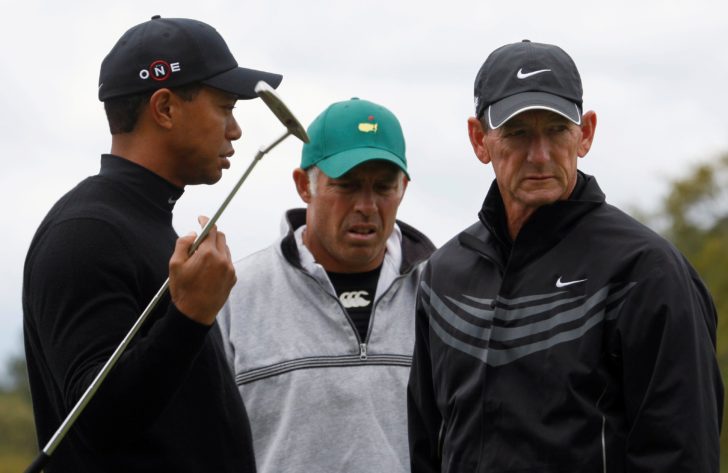 FILE PHOTO: Woods of the U.S. talks with his caddie Williams and swing coach Haney on the practice green during a practice round for 2009 Masters golf tournament at the Augusta National Golf Club in Augusta