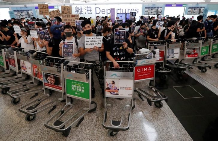 Anti-government protesters stand at a barricade made of trolleys during a demonstration at Hong Kong Airport