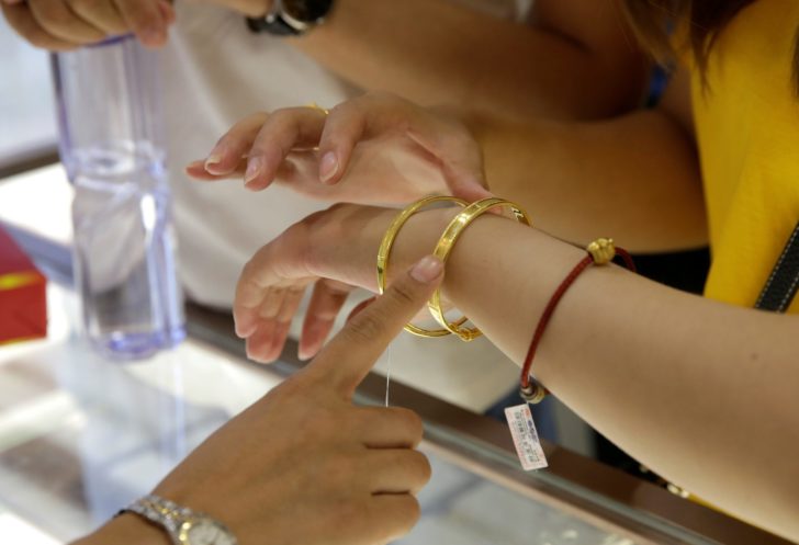 A customer tries on gold bracelets at Caibai Jewelry store in Beijing