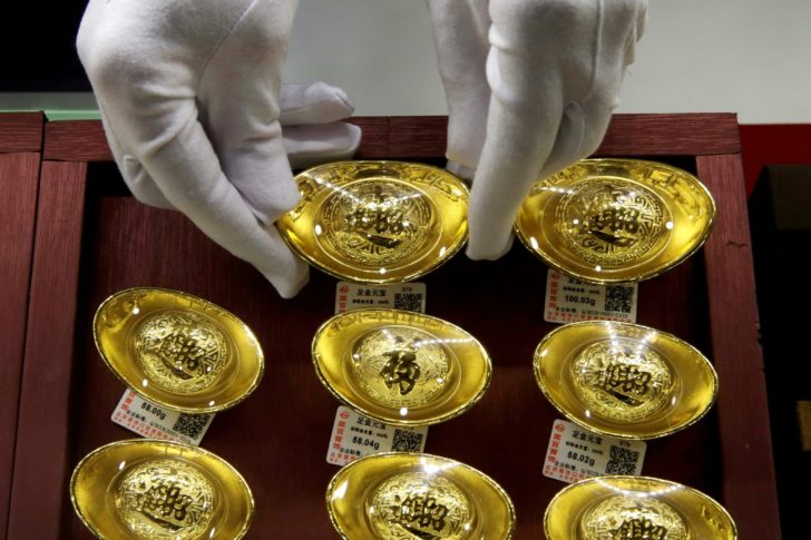 FILE PHOTO: FILE PHOTO: A sales assistant places gold ornaments at Caibai Jewelry store in Beijing