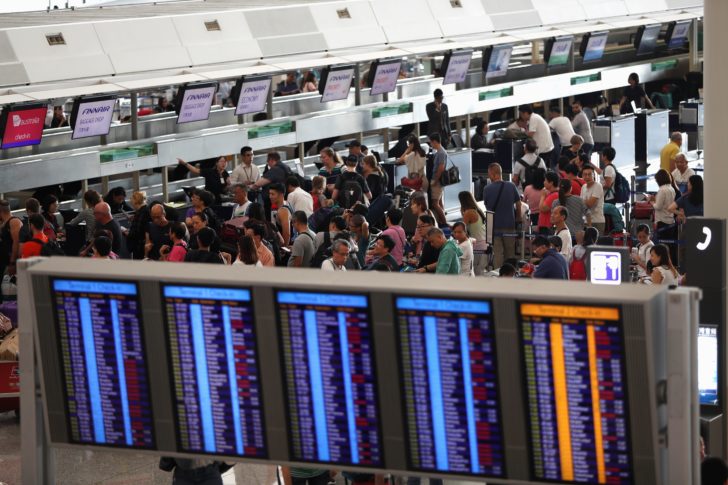 Passengers queue at check-in counters as the airport reopened a day after flights were halted due to a protest, at Hong Kong International Airport, China