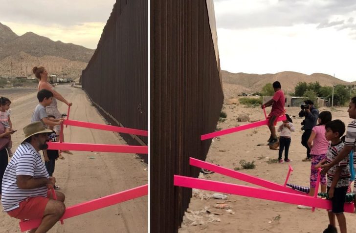 Children and adults play on pink seesaws along the U.S.-Mexico border in Sunland Park
