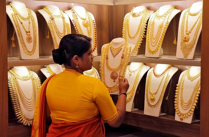 FILE PHOTO: A saleswoman picks gold necklaces to show to a customer at a jewellery showroom in Kochi