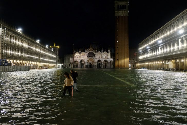 People walk in a flooded St.Mark's Square during a period of seasonal high water