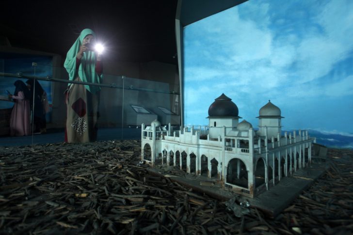 Visitor takes pictures of miniature of Baiturrahman Grand Mosque, which was hit by the tsunami, at Aceh Tsunami Museum in Banda Aceh