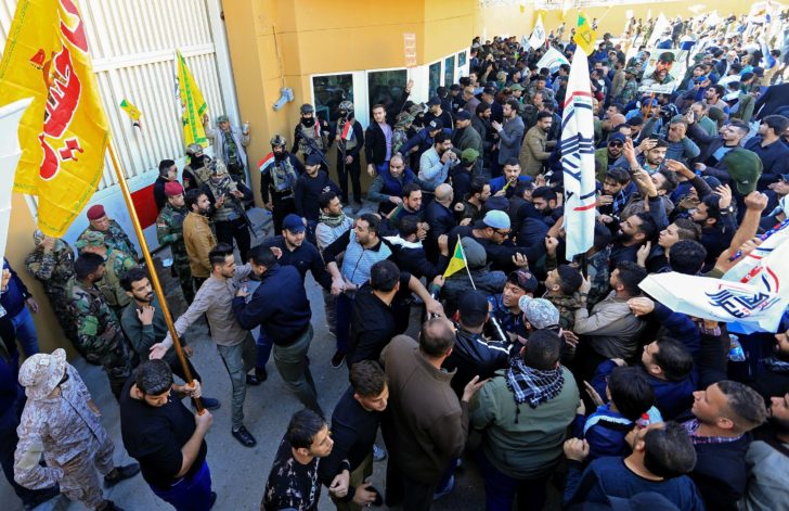 Protesters and militia fighters gather to condemn air strikes on bases belonging to Hashd al-Shaabi, outside the main gate of the U.S. Embassy in Baghdad