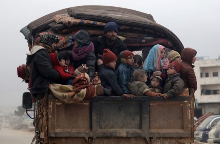 Internally displaced Syrians from western Aleppo countryside, ride on the back of a truck with belongings in Hazano near Idlib