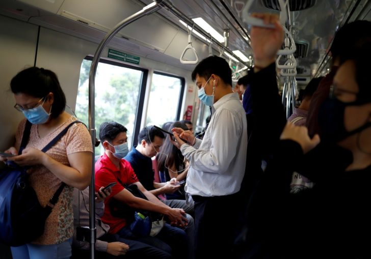 FILE PHOTO: FILE PHOTO: Commuters wearing masks in precaution of the coronavirus outbreak are pictured in a train during their morning commute in Singapore