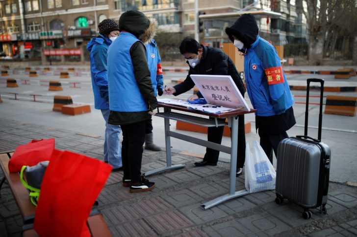 A man wearing a face mask registers at a registration point for people returning or leaving Beijing as the country is hit by an outbreak of the new coronavirus in Beijing