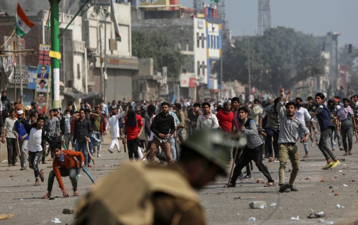 Demonstrators opposing new citizenship law throw pieces of bricks towards riot police and those supporting it during a clash in New Delhi