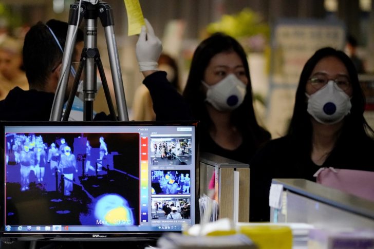 Passengers wearing masks to prevent contracting coronavirus walk past a thermal camera upon their arrival at Incheon International Airport in Incheon