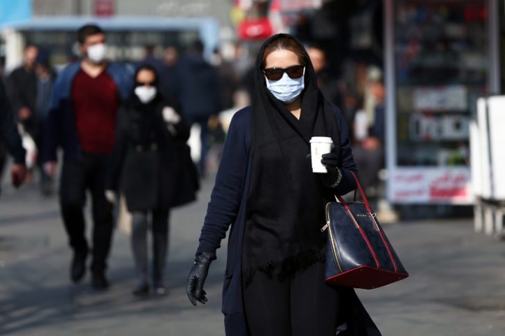 An Iranian woman wearing a protective mask to prevent contracting coronavirus walks in the street in Tehran