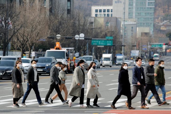 People wearing masks to prevent the coronavirus walk on a pedestrian crossing in downtown Seoul