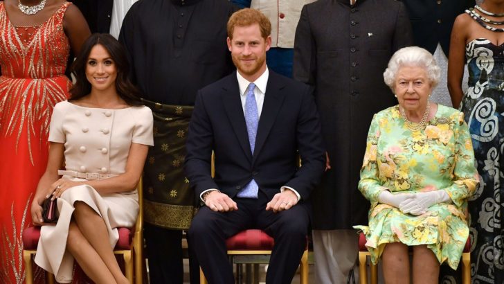 FILE PHOTO: Britain's Queen Elizabeth, Prince Harry and Meghan, the Duchess of Sussex pose for a picture with some of Queen's Young Leaders at a Buckingham Palace reception following the final Queen's Young Leaders Awards Ceremony, in London