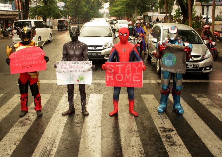 Volunteers wearing superhero costumes carry banners for a campaign against the spread of the coronavirus disease (COVID-19) in Makassar