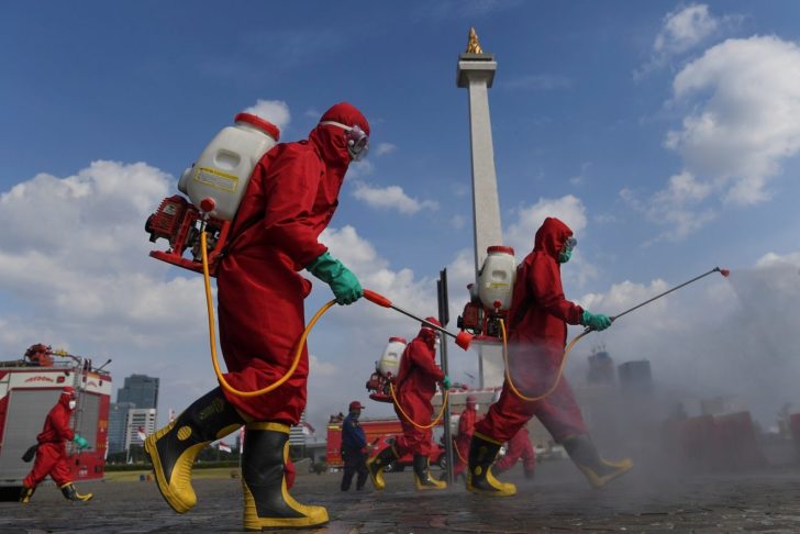 Firefighters wearing protective suits spray disinfectant at National Monument area to prevent the spread of the coronavirus disease (COVID-19)