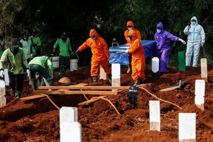 Workers wearing protective suits bury a coffin at the Muslim burial area provided by the government for victims of the coronavirus disease (COVID-19) at Pondok Ranggon cemetery complex in Jakarta