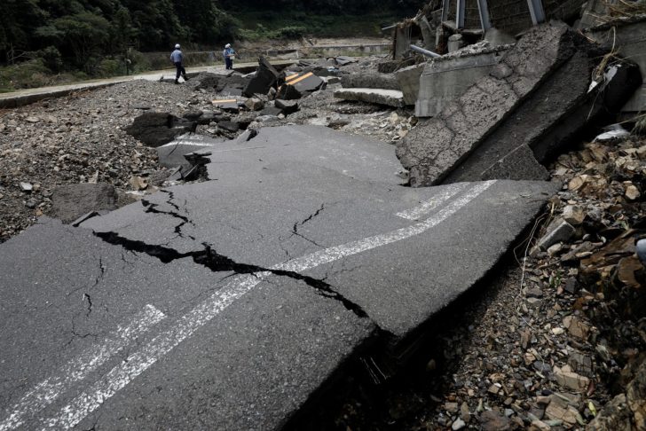 Workers check a damaged road after floods caused by torrential rain, in Kumamura