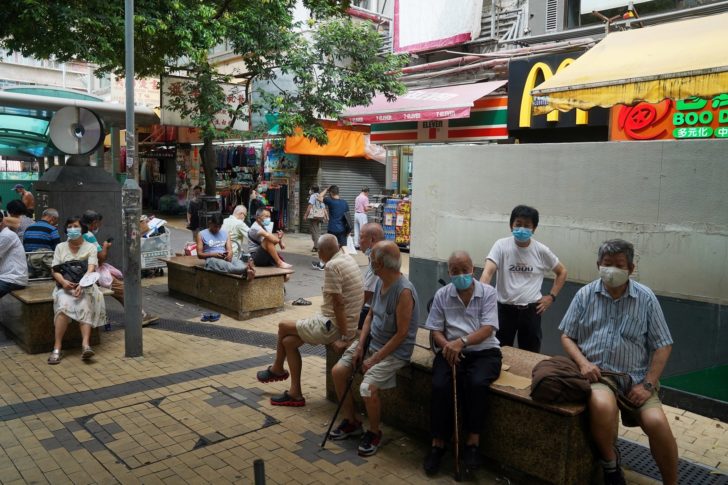 People sit on benches at a shopping street in Hong Kong