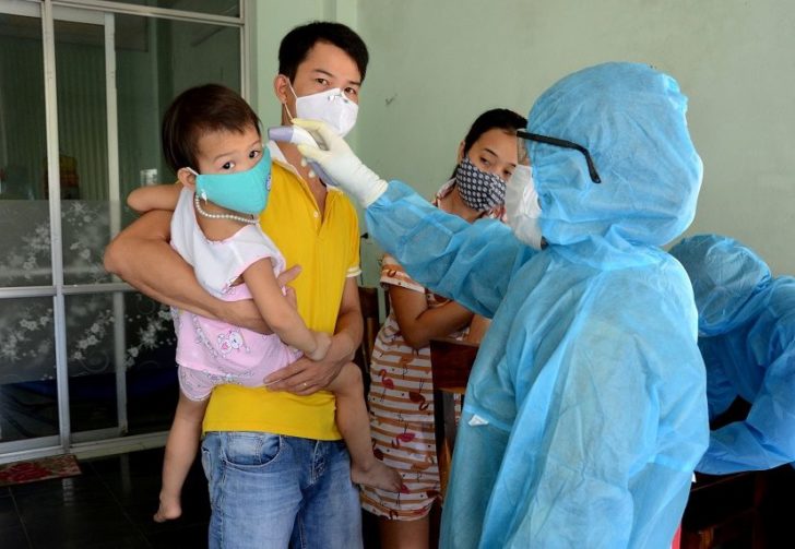 A health worker gets the temperature of residents at the area of a newly found coronavirus infected patient in Da Nang city