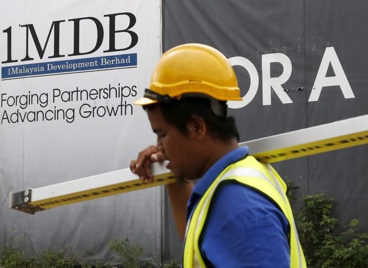 FILE PHOTO: A construction worker walks past a 1Malaysia Development Berhad (1MDB) billboard at the Tun Razak Exchange development in Kuala Lumpur