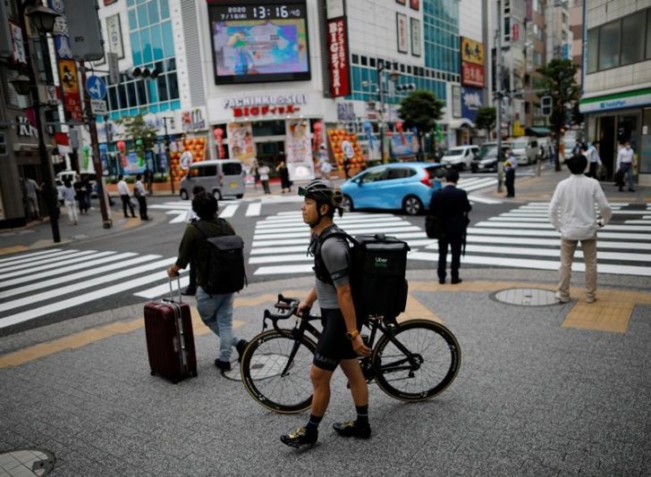 Takenobu Tonegawa walks as he works his part-time job as Uber Eats delivery person amid the coronavirus disease (COVID-19) outbreak, in Tokyo
