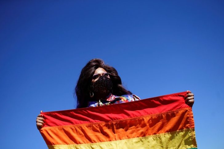 A demonstrator holds a LGBT rainbow flag during a protest against Brazil's President Jair Bolsonaro in front of the National Congress, in Brasilia