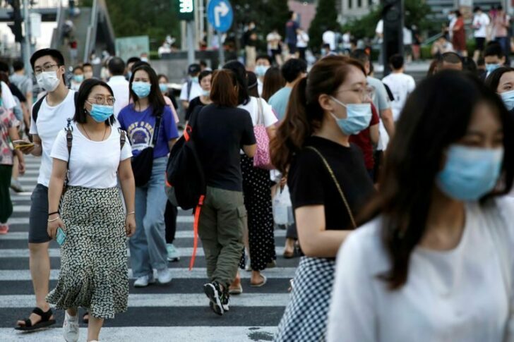 FILE PHOTO: People wearing face masks following the coronavirus disease (COVID-19) outbreak walk across a street at a shopping area in Beijing
