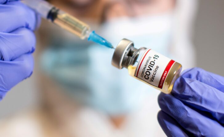 FILE PHOTO: A woman holds a medical syringe and a small bottle labeled