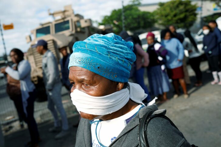 FILE PHOTO: An elderly woman covers her face with a makeshift mask as people queue to collect social grants and shop during a 21 day nationwide lockdown aimed at limiting the spread of coronavirus disease (COVID-19) in Khayelitsha township near Cape Town